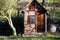 Small garden hut with gutter and rain barrel next to a tree 1