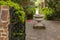 A small garden with trimmed shrubs, beautiful flowering plants and trees and a stone decorative bird bath