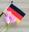 Small German flag with pink tulips on a wood background