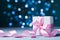 Small gift box or present with pink bow ribbon against magic bokeh background. Greeting card for Christmas, New Year or wedding.