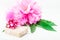 Small gift with ribbon and peony over white wooden background