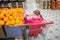 A small girl buys oranges sitting in a grocery supermarket cart