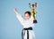 Small girl with champion cup. martial arts. winner little girl in gi sportswear. practicing Kung Fu. childhood. knockout