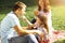 Small girl feeding daddy with marshmallow on picnic in the park