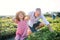 Small girl with grandfather picking strawberries on the farm.