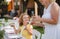 Small girl with grandmother outdoors on garden party in summer, eating.