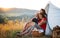 Small girl with grandparents sitting in shelter tent in nature at sunset, resting.