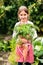 A small girl harvesting vegetables on allotment, holding a big carrot.