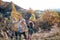 Small girl with mother and grandmother collecting rosehip fruit in autumn nature.