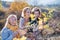 Small girl with mother and grandmother collecting rosehip fruit in autumn nature.