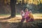 Small girl with mother and grandmother resting in autumn forest.