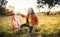 A small girl playing with a rainbow hand kite in autumn nature at sunset.