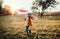 A small girl playing with a rainbow hand kite in autumn nature at sunset.