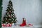 Small girl in the red dress at the Christmas tree gifts new year holiday