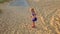 Small Girl Runs along Rocky Path by Grass Sand Dunes at Sunset