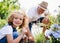 Small girl with senior grandfather gardening in the backyard garden.