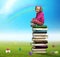 Small girl sits on the pile of books