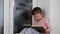 Small girl sits on windowsill behind the frozen window. Cute little girl sits on window ledge and reads the book.