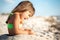 Small girl sitting and playing with sand on beach