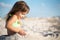 Small girl sitting and playing with sand on beach