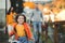 Small girl with unrecognizable parents in the background running in park in autumn.