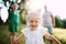 A small girl with unrecognizable parents in sunny summer nature.