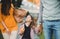 A small girl with unrecognizable parents walking outdoors in park in autumn.