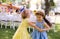 Small girls dancing outdoors in garden in summer, birthday celebration concept.