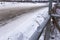 A small glass ball lies in the winter on the railing in the snow against the background of a turn