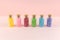 Small glass bottles with corks with multicolored shiny sequins asterisks stand in a row on a pink background.