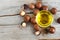 Small glass bowl with macadamia nut oil and macadamia nuts over the old wooden background.