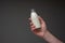 Small glass milk bottle with cap held in hand by Caucasian male. Close up studio shot,  on gray background