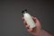 Small glass milk bottle with cap held in hand by Caucasian male. Close up studio shot,  on gray background