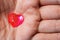 Small glass red heart in a male palm. The subjects of medicine, sociology, health preservation and declaration of love