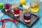 Small glasses with colorful drinks on a wooden board