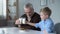 Small grandson clinking glasses of milk with his grandfather, nutritious lunch