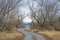 Small gravel road framed with bushes leads to infinity.