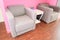 Small gray armchairs side by side in front of a pink wall