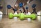 Small green dumbbells on the wooden floor. Fitness gears in the gym with girls doing exercises with balls on the background. Sport