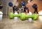 Small green dumbbells on the wooden floor. Fitness gears in the gym with girls doing exercises with balls on the background. Sport