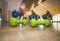 Small green dumbbells on the wooden floor. Fitness gears in the gym with girls doing exercises with balls on the background. Sport