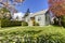 Small green house exterior with spring blooming trees.