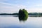 A small green island reflecting in a blue lake