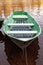 Small green rowboat is moored at coast of a still lake