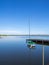 Small green sailing boat is attached to a lake at a landing stage