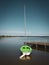 Small green sailing boat is attached to a lake at a landing stage