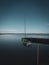 Small green sailing boat is attached to a lake at a landing stage