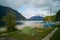 Small green tent and boats next to beach on campground camping Walchensee in the alpine upland with lake and mountain Herzogstand