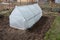 Small greenhouse made of metal frame and plastic wrap in spring