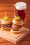 Small grilled burgers served to share with beer on rustic table